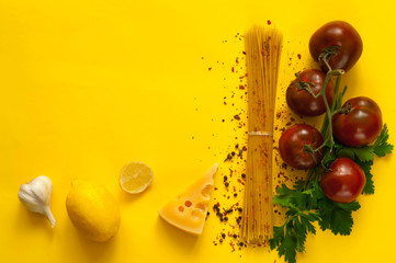 tomatoes kumato and ingredients for cooking pasta on yellow background. Frame made of organic products. Concept of vegetarian food and healthy eating.Flat lay, copy space, close up