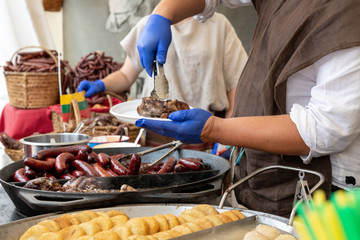 Chef hands in gloves and traditional costume is putting meat on food festival