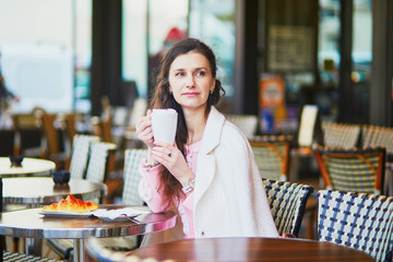 Woman drinking coffee in outdoor cafe or restaurant, Paris, France