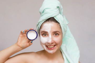 Woman with face cream on her face is showing a moisturizing cream. Face skin care concept.