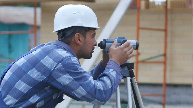 Male construction worker working with theodolite, level tool
