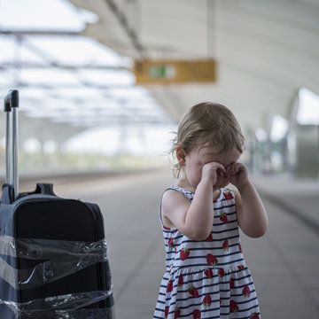  little sweet girl with a large travel suitcase on a deserted railway perone cries and a third eye.