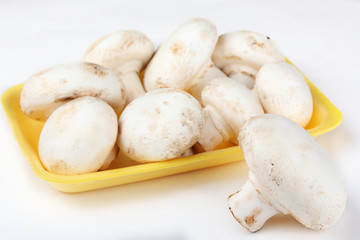 Fresh champignons in the yellow plastic tray isolated on a white