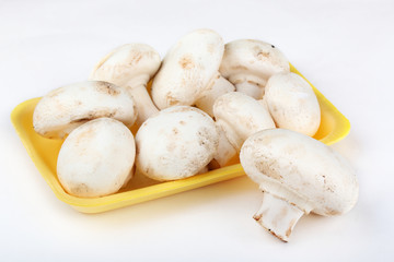 Fresh champignons in the yellow plastic tray isolated on a white