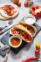 Fresh delicious mexican tacos and food ingredients on concrete background.