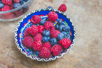 Close up and top view of mixed healthy fresh summer berries or food in glass bowls on wooden table or background. Healthy breakfast or summer diet plan to loose weight