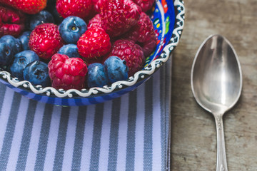Close up and top view of mixed healthy fresh summer berries or food in glass bowls on wooden table or background. Healthy breakfast or summer diet plan to loose weight