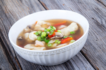 dumpling soup with green onion on wood table
