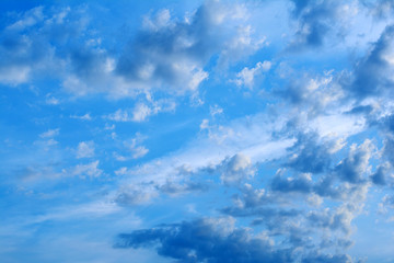 Evening blue sky with clouds at sunset. Clouds are illuminated by the rays of the setting sun.