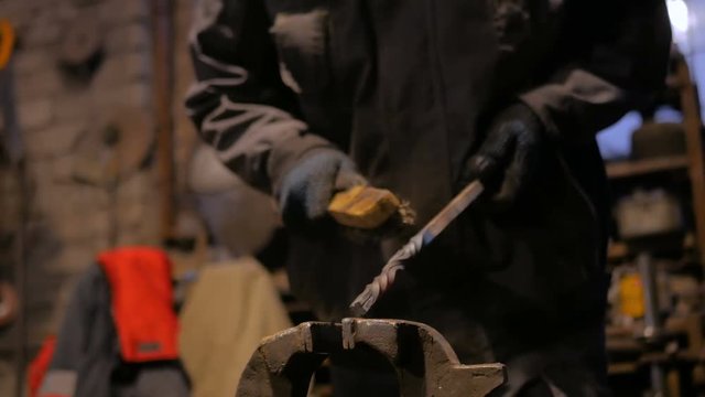 Professional blacksmith working with metal at forge, workshop. Handmade, craftsmanship and blacksmithing concept