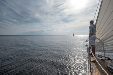young european man standing at edge of yacht looking at sea. - Powered by Adobe