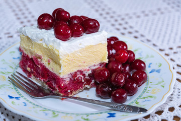a delicious piece of cake with cherries and cream served on a plate