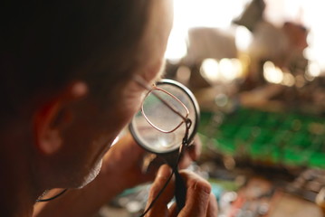 Fototapeta na wymiar Man Looking At Circuit Board With Magnifying Glass