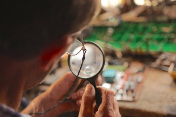 Man Looking At Circuit Board With Magnifying Glass