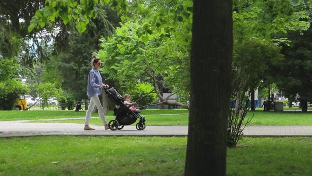 mother with a stroller walks in the park