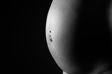 Art nude, naked pregnant woman on black studio background, pregnancy concept