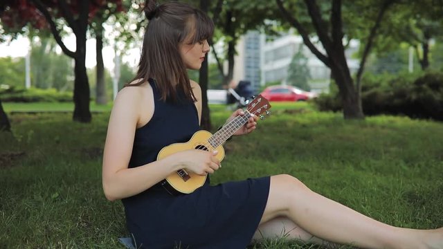 Young woman play on ukulele, little guitar