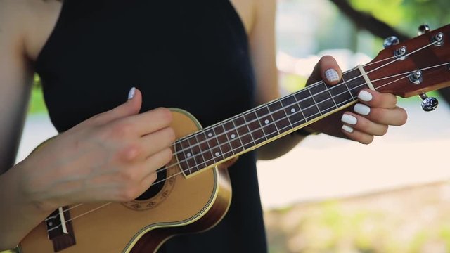 Young woman play on ukulele, little guitar in day off