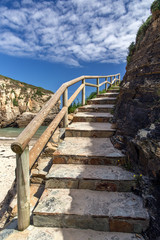 Stone ladder with a wooden handrail along the rock