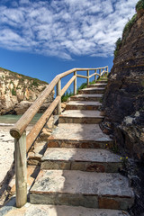 Obraz premium Stone ladder with a wooden handrail along the rock