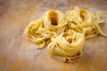 fresh tagliatelle pasta on a wooden table with flour