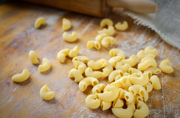 fresh Elbow pasta on a wooden table with flour