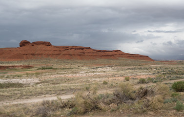 A Prairie with Red Rock Mountains in the distance and storm clouds overhead.