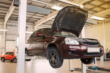 car in a car service on a lift with an open hood