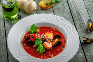 Tomato soup with sea food on a wooden table. Delicious Italian healthy food in a plate.