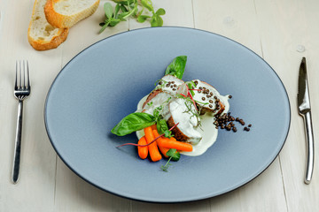 Plate with meal made of meat medallions, cream sauce and fresh vegetables on an expensive plate. Healthy meat food with toasted bread.