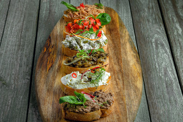 Bruschetta and antipasti crostini set made of baguette tomato, meat pate, olives, cream cheese and tuna salad. Classic Italian food.