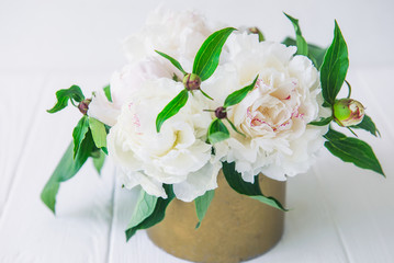 Fresh bouquet of white peonies in vintage bowl on light wooden background. Wedding flowers. Card Concept. Selective focus. Copy space for text.