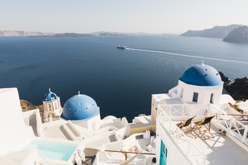 View over Aegean sea, Oia village and volcano caldera with luxury hotel and infinity swimming pool...