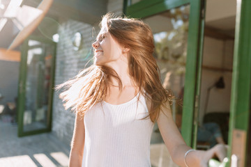 Happy incredible lovely woman with long hair waving head and has fun outside in sunlight and her hair flying at camera, happiness, good mood, summer