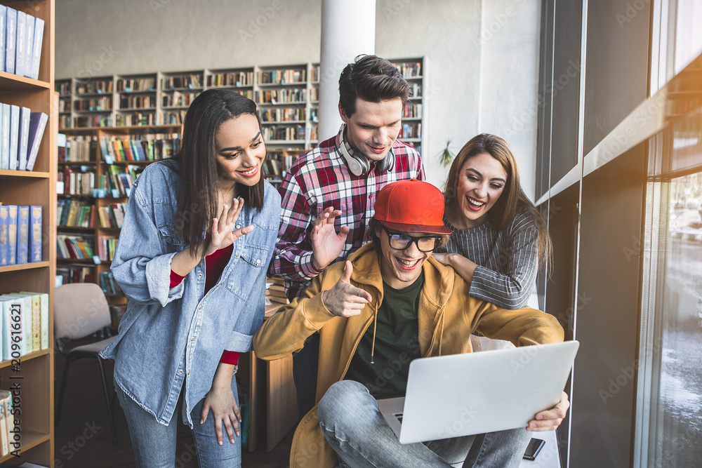 Poster portrait of cheerful men and outgoing girls gesticulating hands in notebook computer while locating 