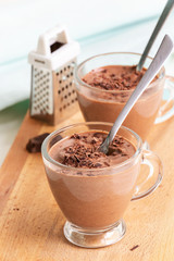 Healthy dessert chocolate pudding serving cups wooden cutting boarding. Selective focus.