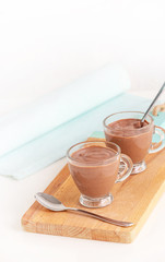 Healthy dessert chocolate pudding serving cups wooden cutting boarding. Selective focus. Copy space. Vetical image.