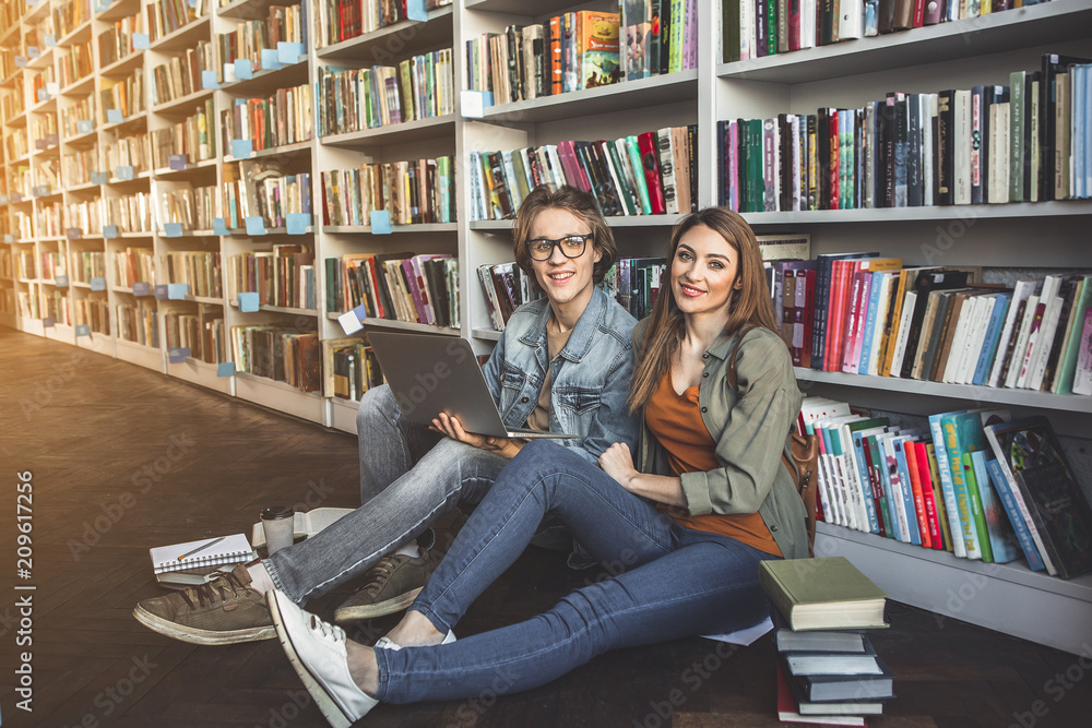 Poster full length portrait of satisfied man and beaming girl using notebook computer while leaning against