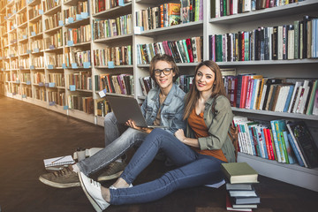 Full length portrait of satisfied man and beaming girl using notebook computer while leaning against door