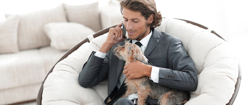 businessman is holding his pet and talking on a smartphone
