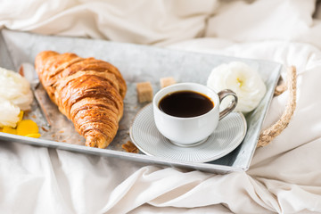 Fresh Croissant, Cup of Coffee and Ranunculus Flowers. Breakfast