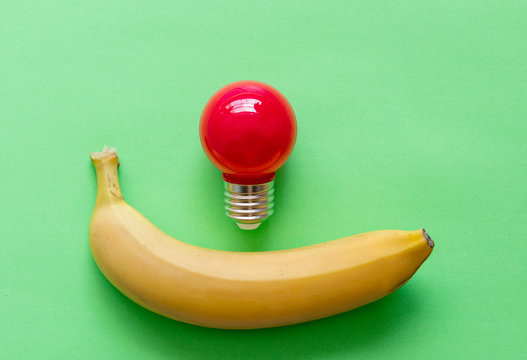 Yellow banana with bulb on green background. Natural light