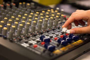 Hand of woman adjusts equalizer on mixing console. Sound engineer working on professional audio...