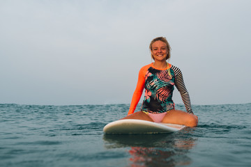   girl floats sitting on the surf on horseback and smiling