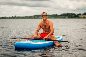 a man in shorts sitting relaxed on   sup surf