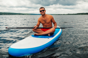 a man in shorts sitting relaxed on  sup surf