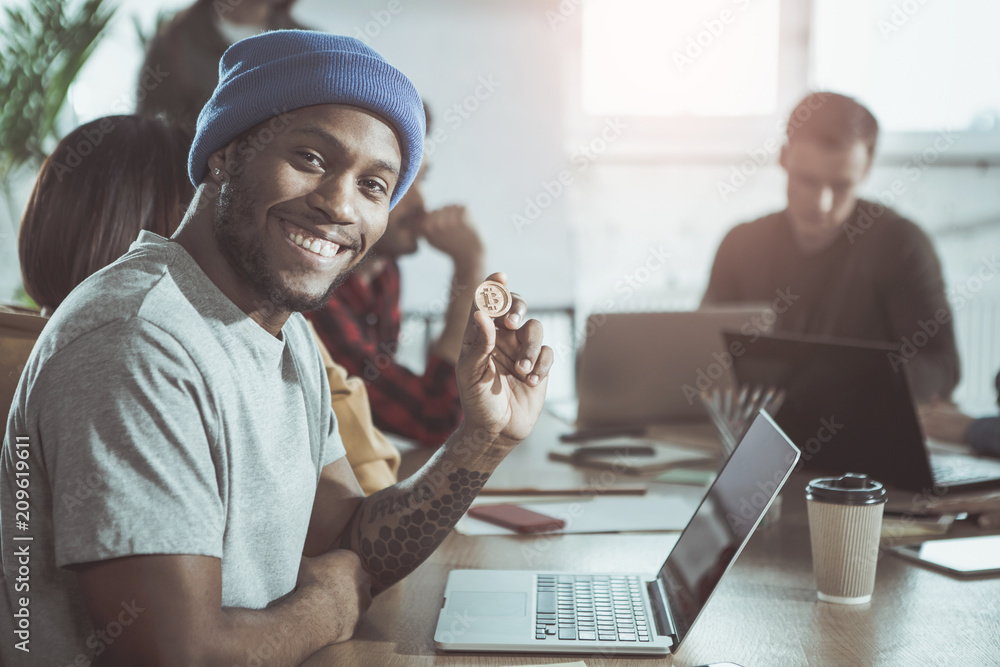 Poster cryptocurrency concept. portrait of happy young man with laptop is sitting at table with bitcoin in 
