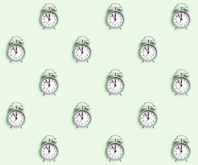 Seamless pattern with retro style alarm clock over the pastel mint green background