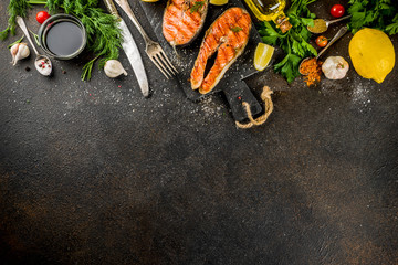Grilled salmon fish steaks with ingredients lemon, herbs, olive oil, slate cutting board, dark rusty background copy space