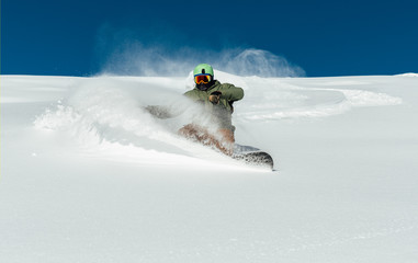 man snowboarder curved and brakes sprinkling snow on   freeride slope of fresh deep snow